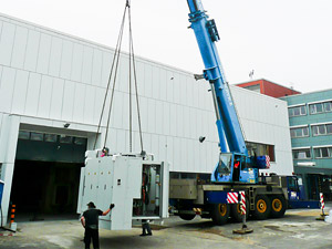 Foto: Ein Kranarm hebt die Werkzeugmaschine vor das Eingangstor der Laborhalle Rasmussenbau.