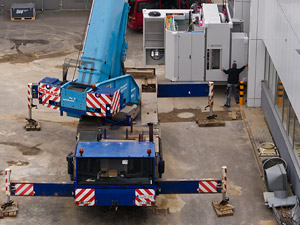 Foto: Ein Kranarm hebt die Werkzeugmaschine vor das Eingangstor der Laborhalle Rasmussenbau.