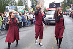 Foto: Drei Teilnehmer laufen auf einem Festumzug und winken den Zuschauern.