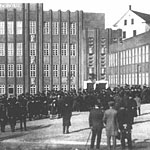 Foto: Schulweihe. Aussenansicht mit dem Gebäude und vielen Teilnehmern der Einweihungsveranstaltung.