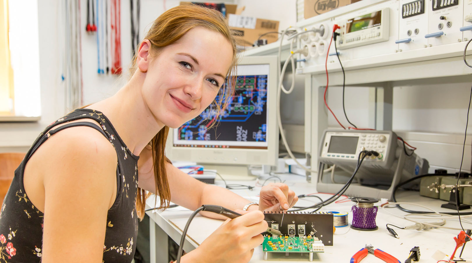 Photo: A female student sits at a laboratory workstation and solder a circuit board. (source: whz/H. Gerischer)
