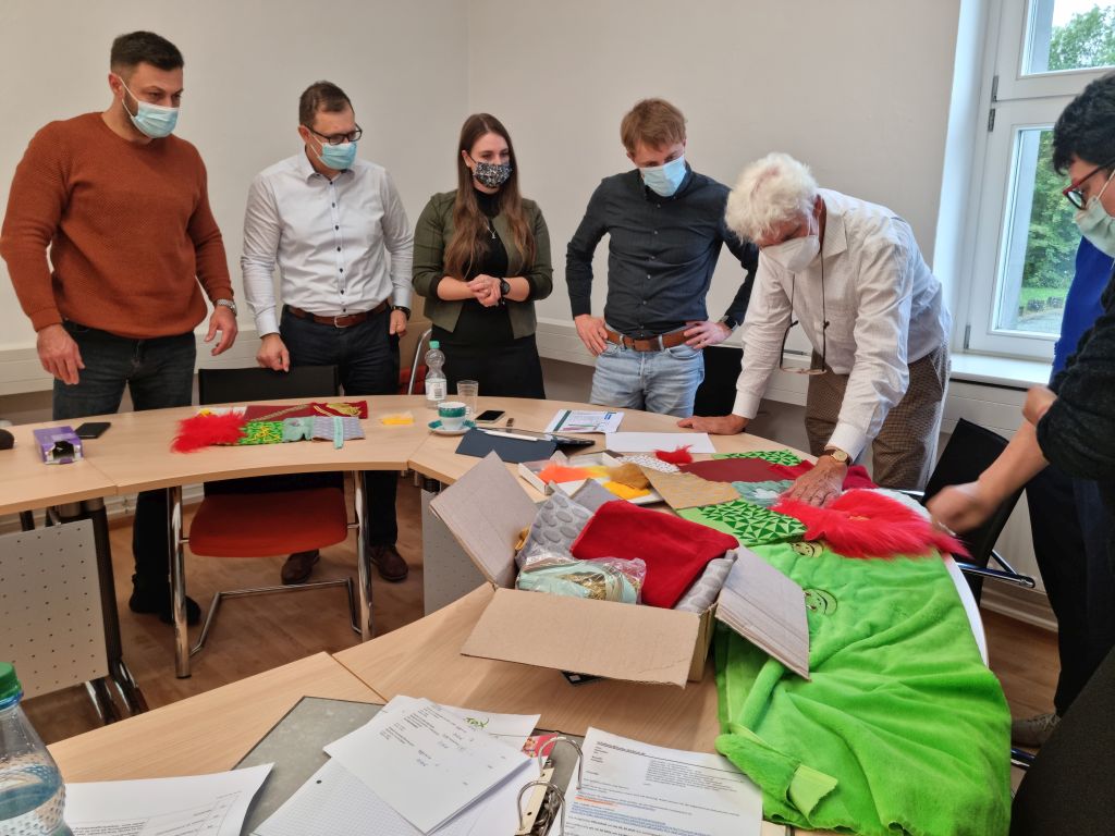 Foto: Personen am Tisch, Textilien auf Tisch