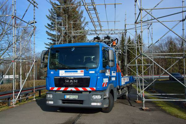 Foto 3: LKW mit Versuchsaufbau steht unter einem Gerüst.