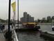Foto: Blick auf eine Anlegestelle am Fluss mit einem Boot und Passanten.
