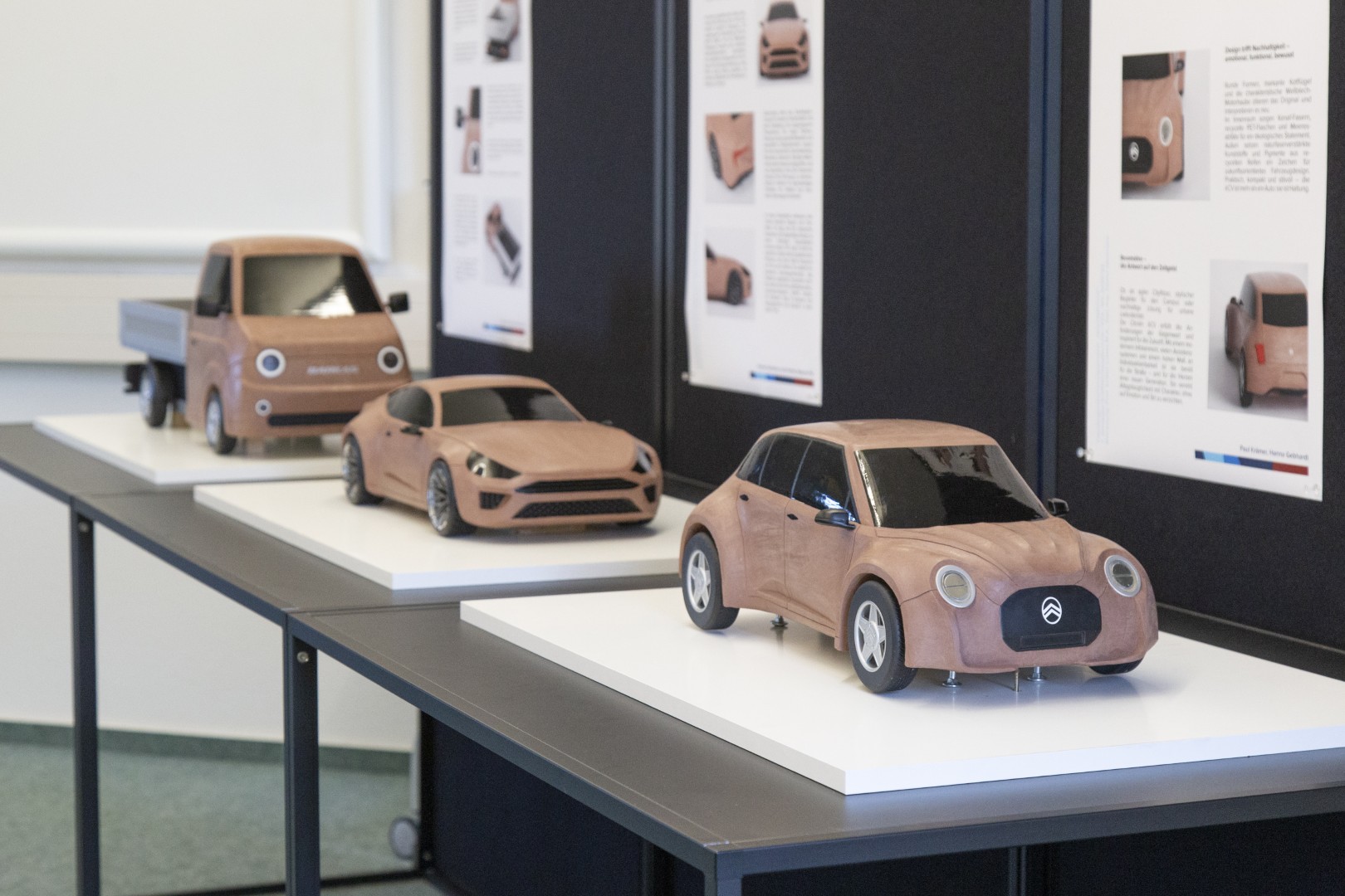 Drei Fahrzeugmodelle aus Industrieknete stehen hintereinander aufgereit da.