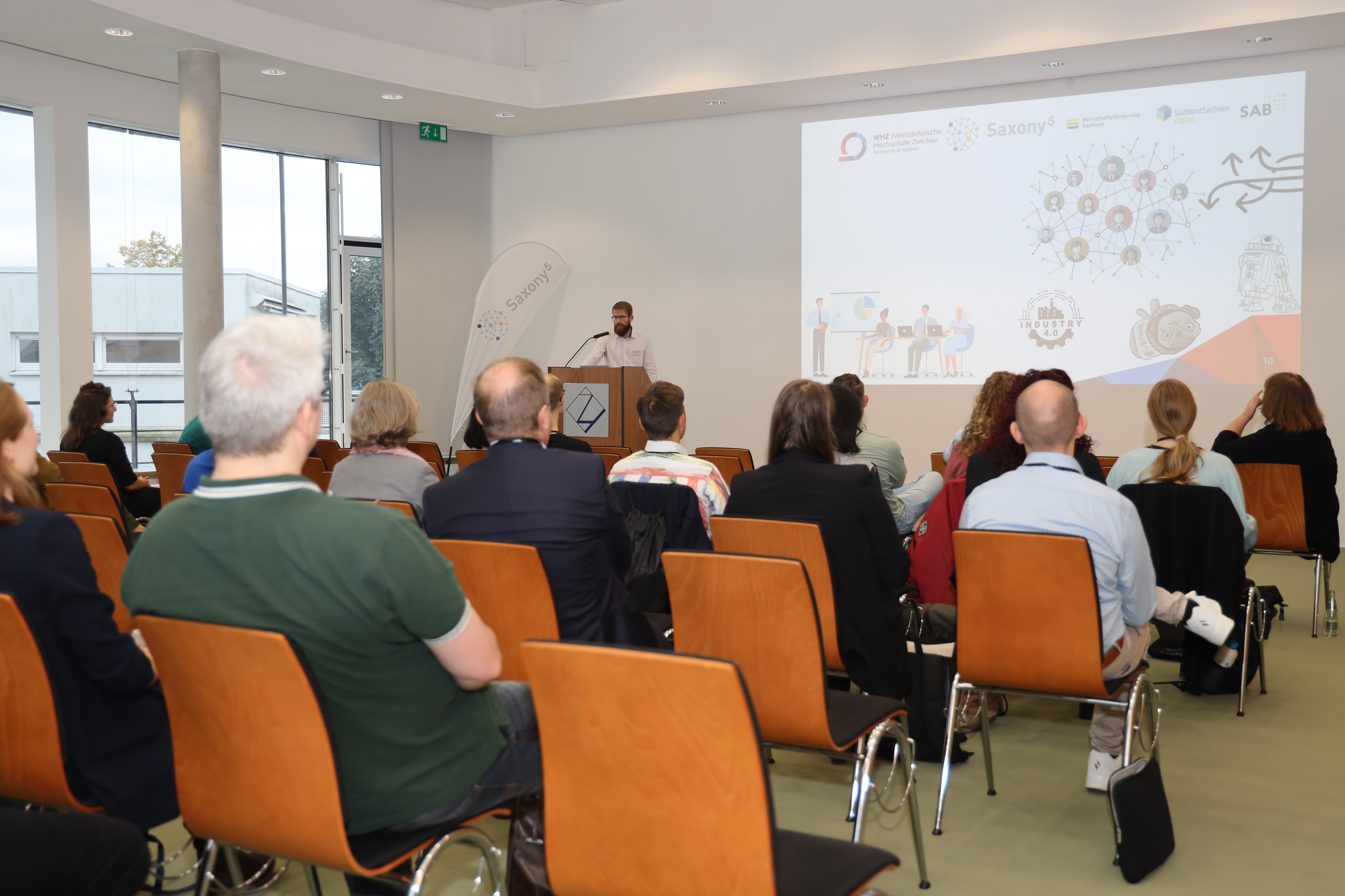 Redner mit Folie zum Thema Aufbau von Resilienz im Unternehmen mit Zuhörern im Vordergrund