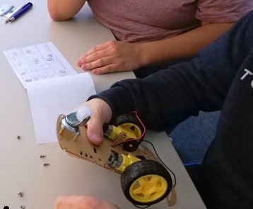 Foto: Ein Schüler hält eine Modellfahrzeugkonstruktion in der Hand.
