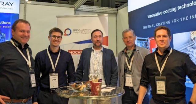 Fünf Teilnehmer am Messestand stehend blicken in die Kamera