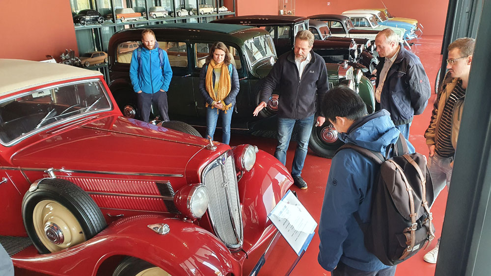 Der Dekan der Fakultät Kraftfahrzeugtechnik Prof. Schubert führt durch das Forum Mobile, wo die Gruppe einen Oldtimer bestaunt. | Quelle: WHZ