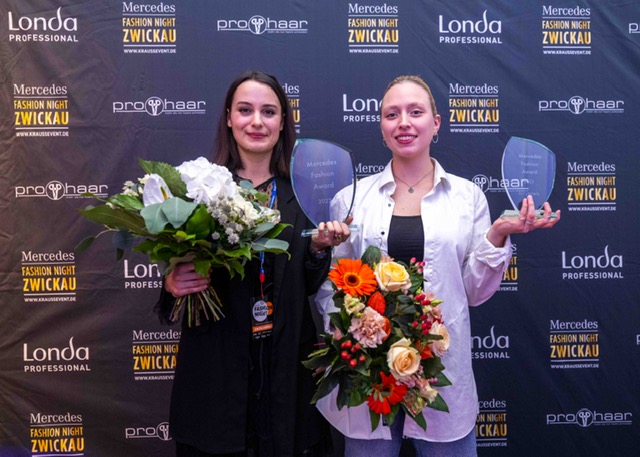 Zwei junge Frauen stehen nebeneinander und haben jeweils einen Preis und einen Blumenstrauß in der Hand.