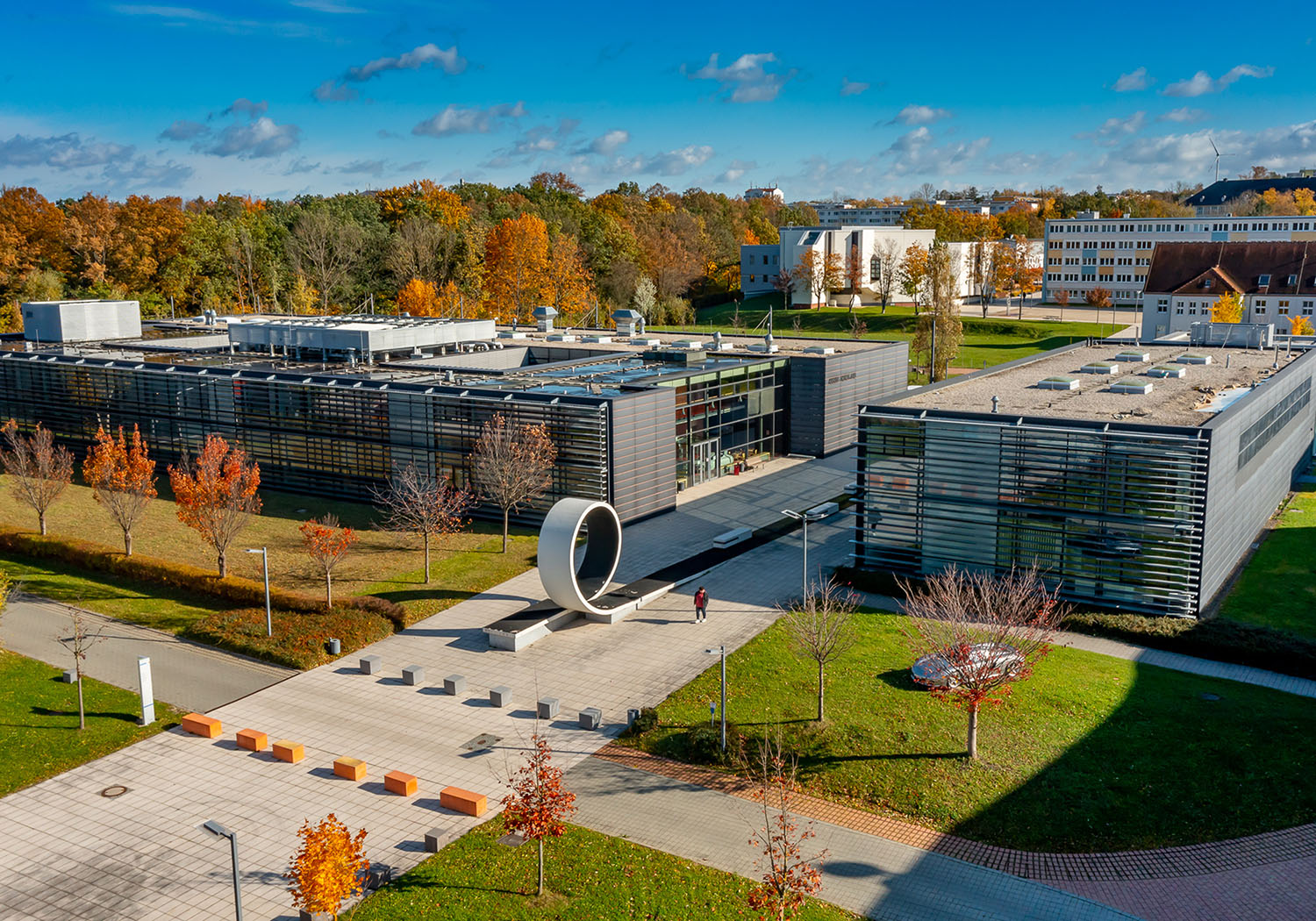 Hochschulcampus im Herbst mit vielen Gebäuden bei blauem Himmel