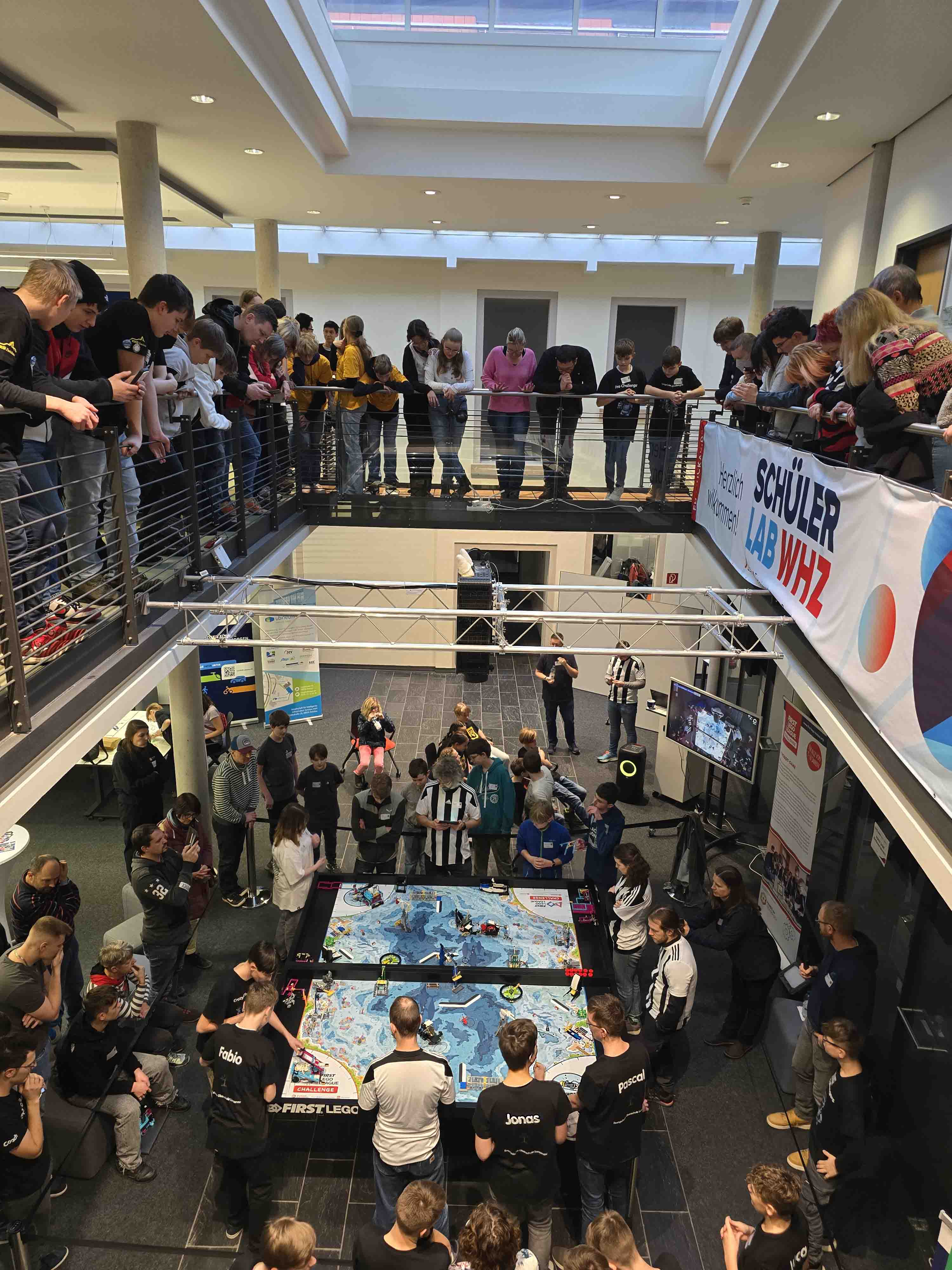 Besucher blicken in einem Lichthof auf einen Lego-Spieltisch, 