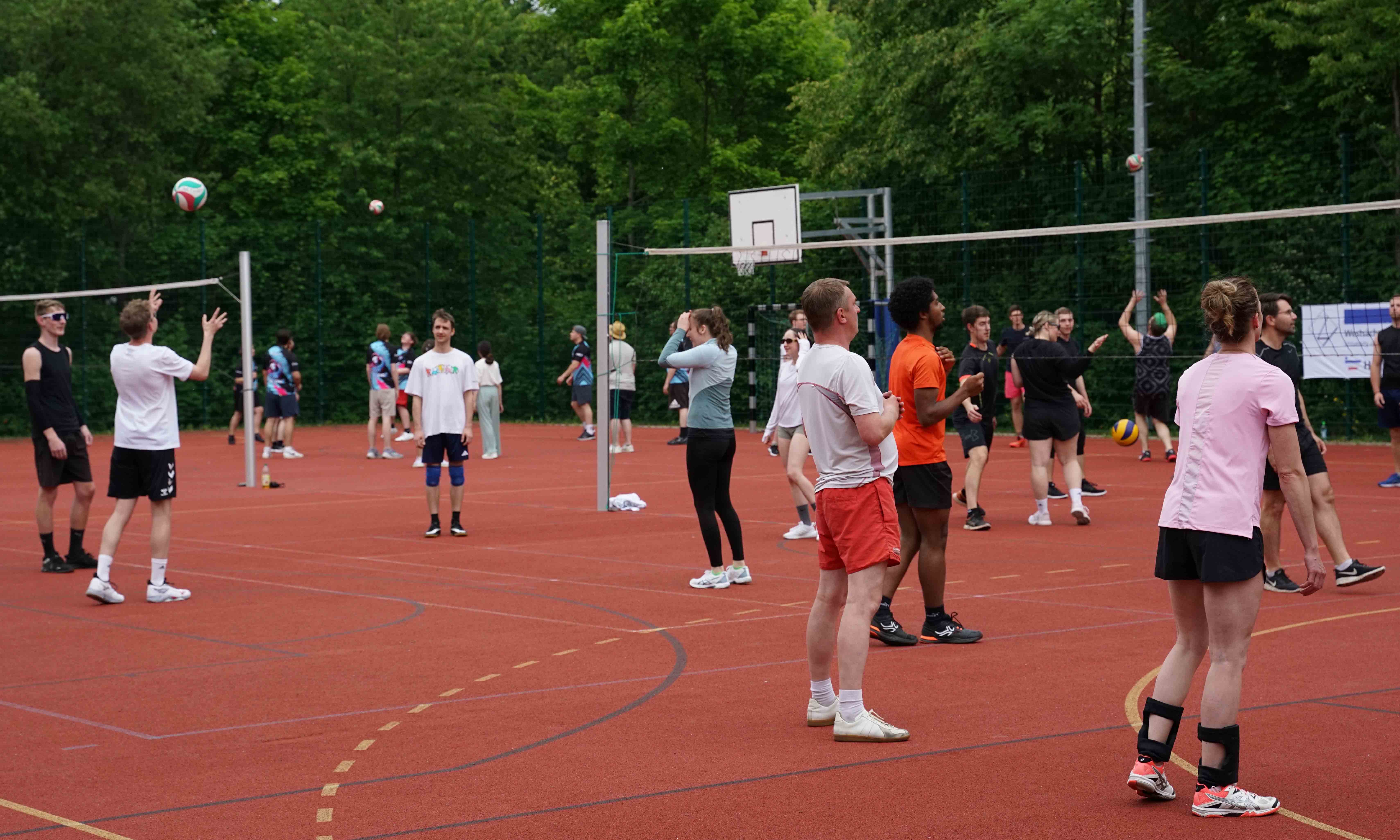 Personen spielen Volleyball auf einem Kleinfeld im Freien. 