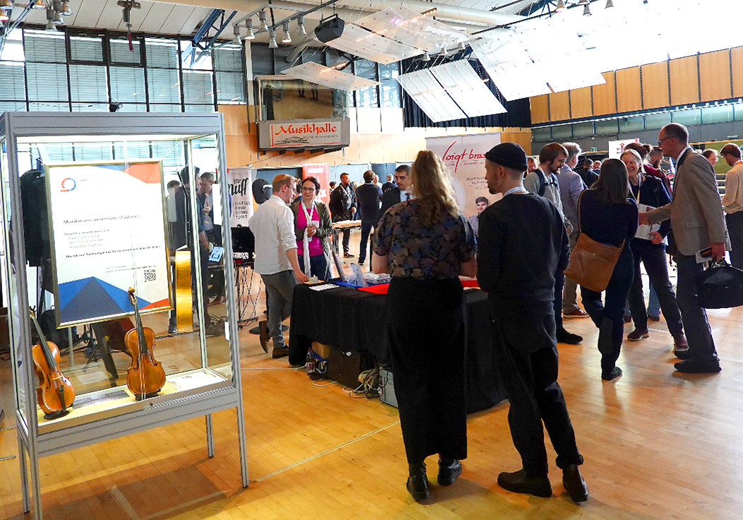 Personen unterhalten sich in einer Ausstellungshalle.