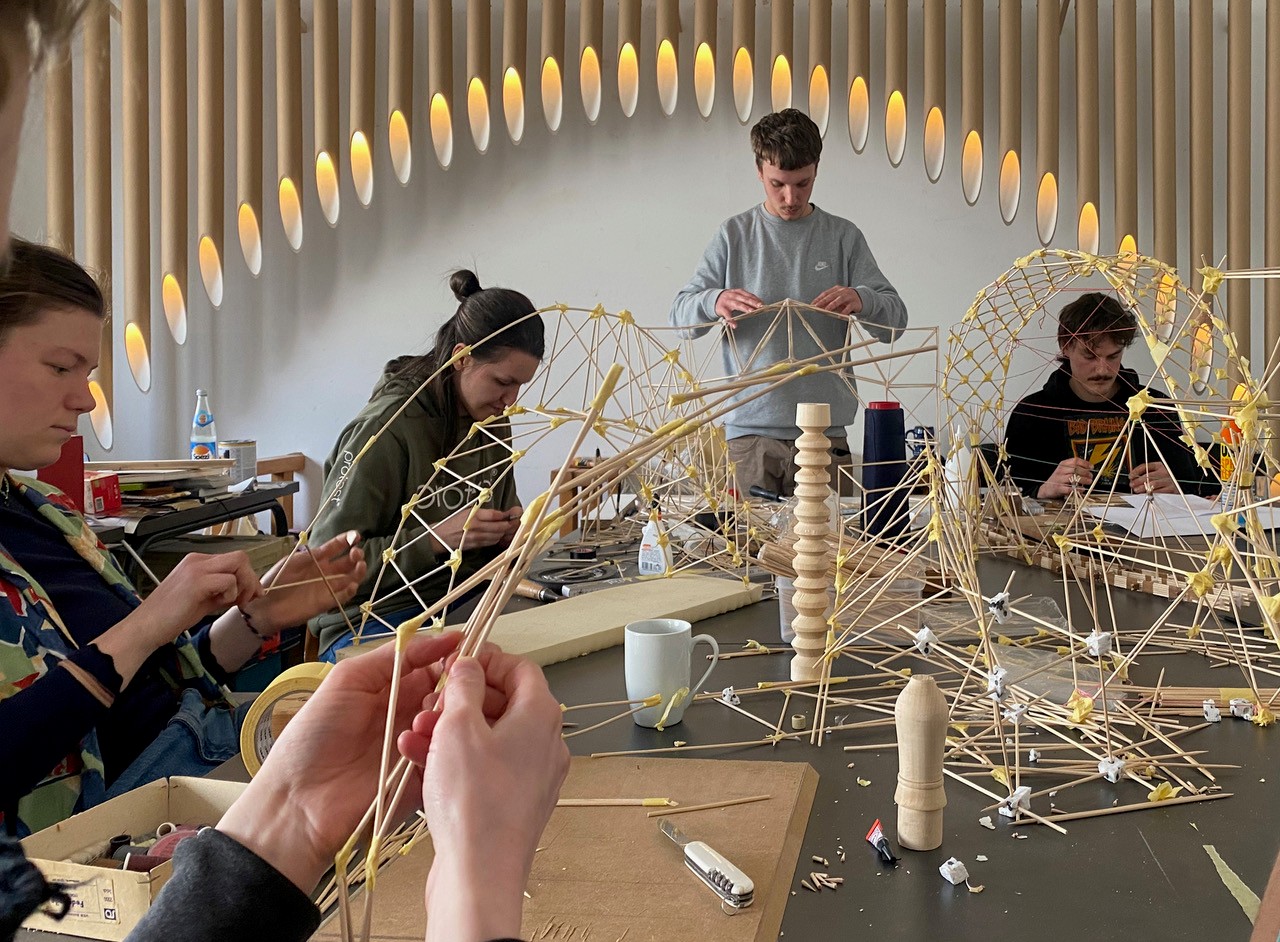 Studenten sitzen an einem Tisch und arbeiten an einer weihnachtlichen Dekoration. 