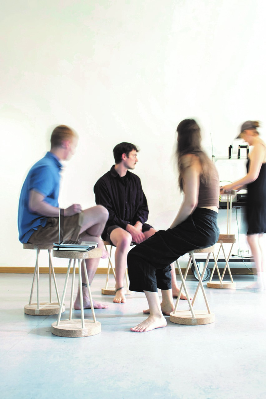 Vier Studenten sitzen in lockerer Atmosphäre auf modernen Hockern. 