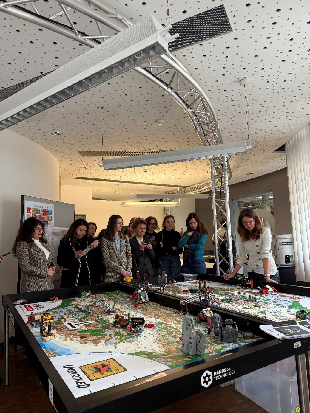 Eine Gruppe von Personen betrachtet einen Lego-Spieltisch. 