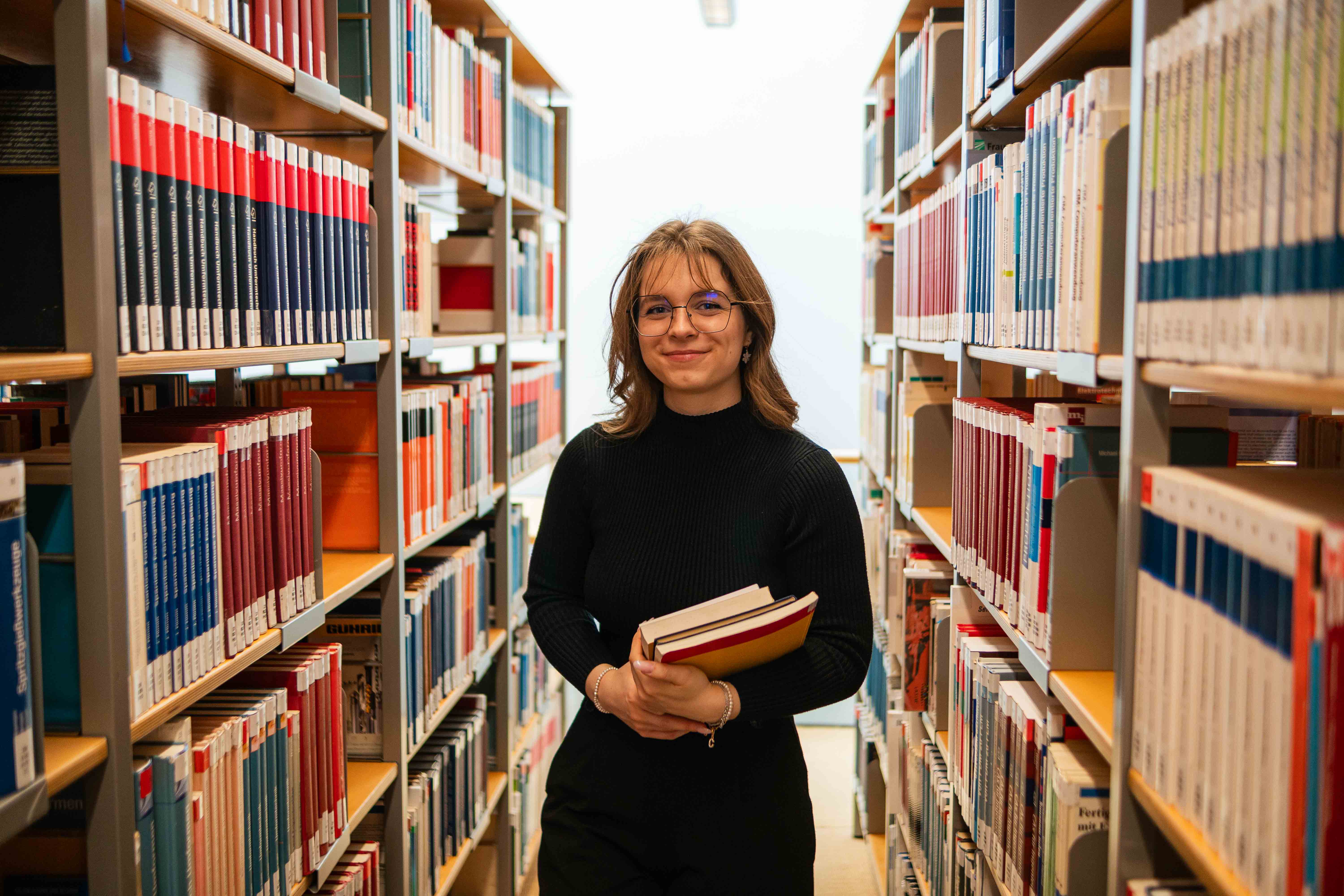 Eine Studentin steht in der Hochschulbibliothek. 