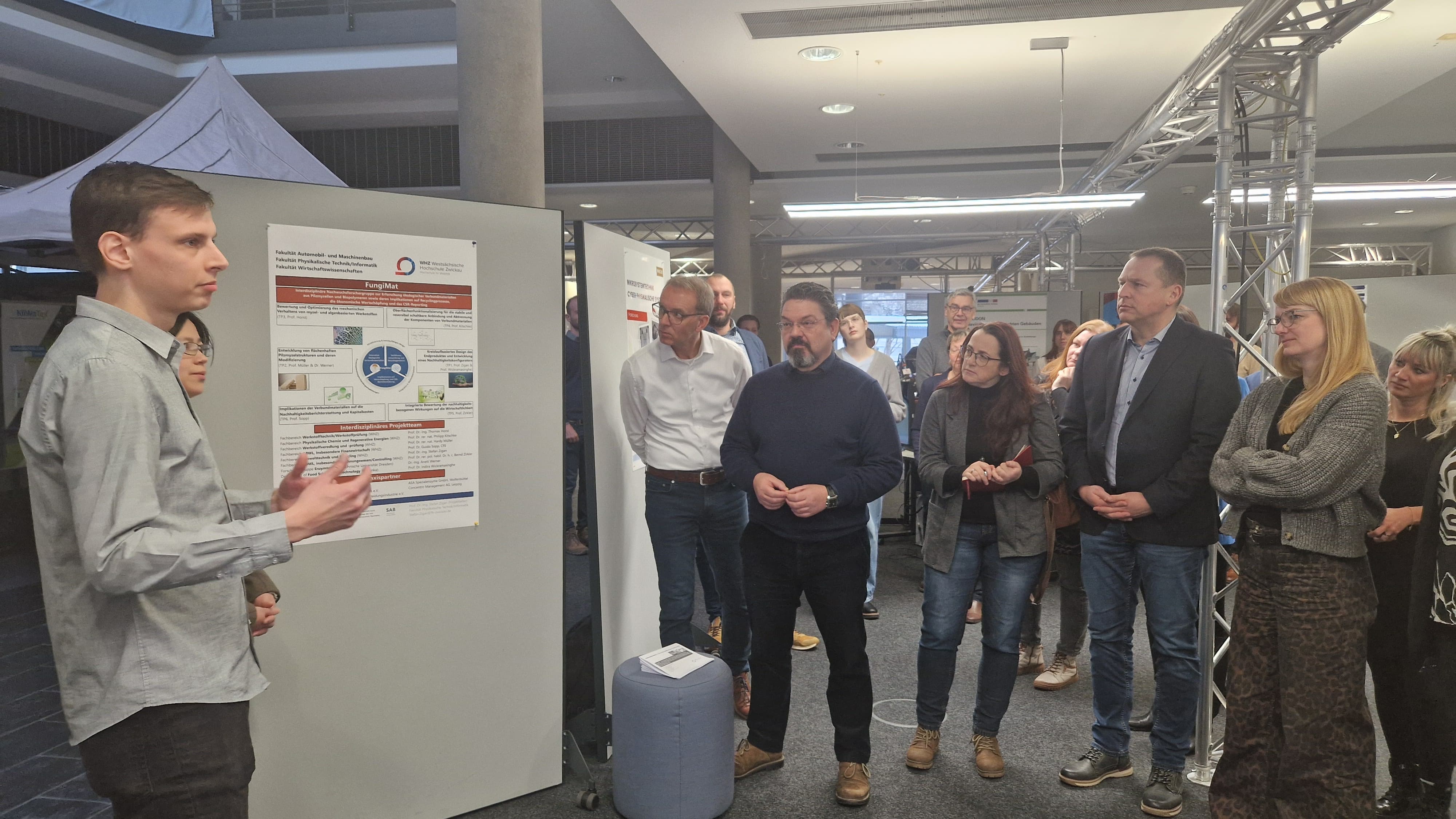 Ein junger Wissenschaftler erklärt Anwesenden sein Projekt. 