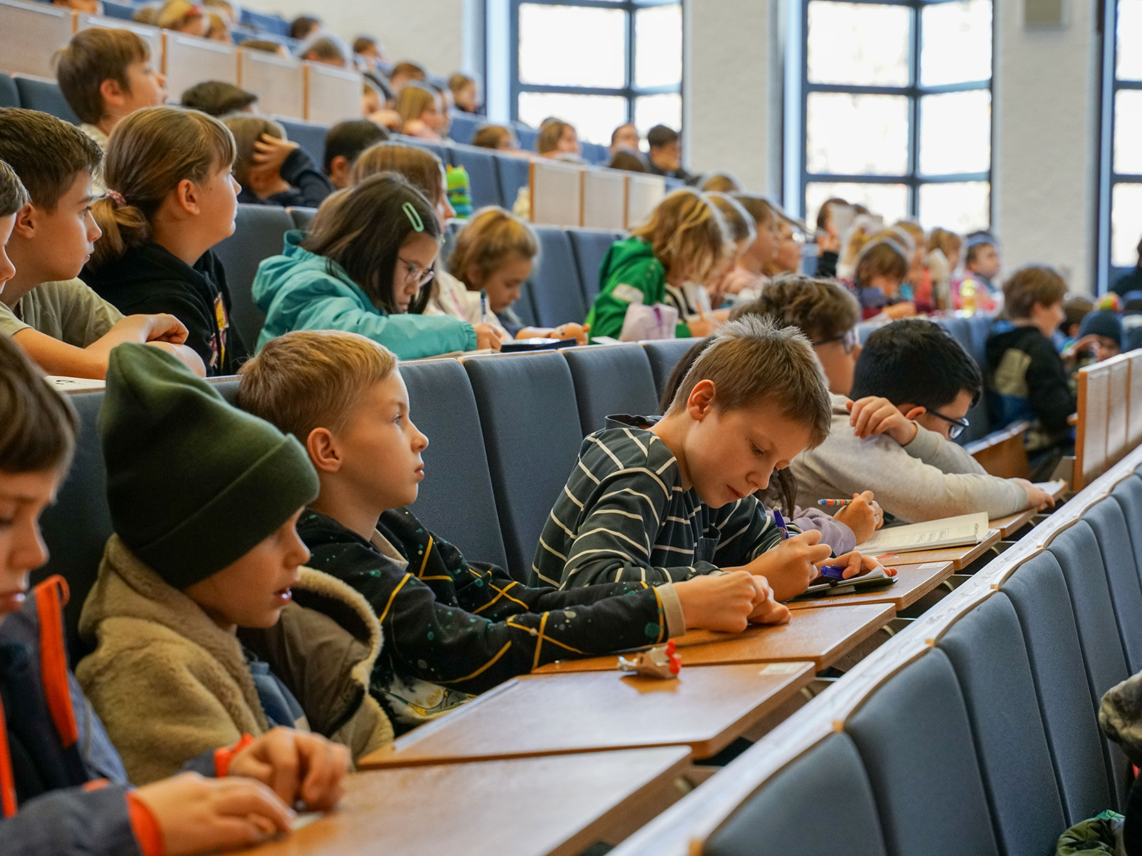 Kinder sitzen in einem Hörsaal.