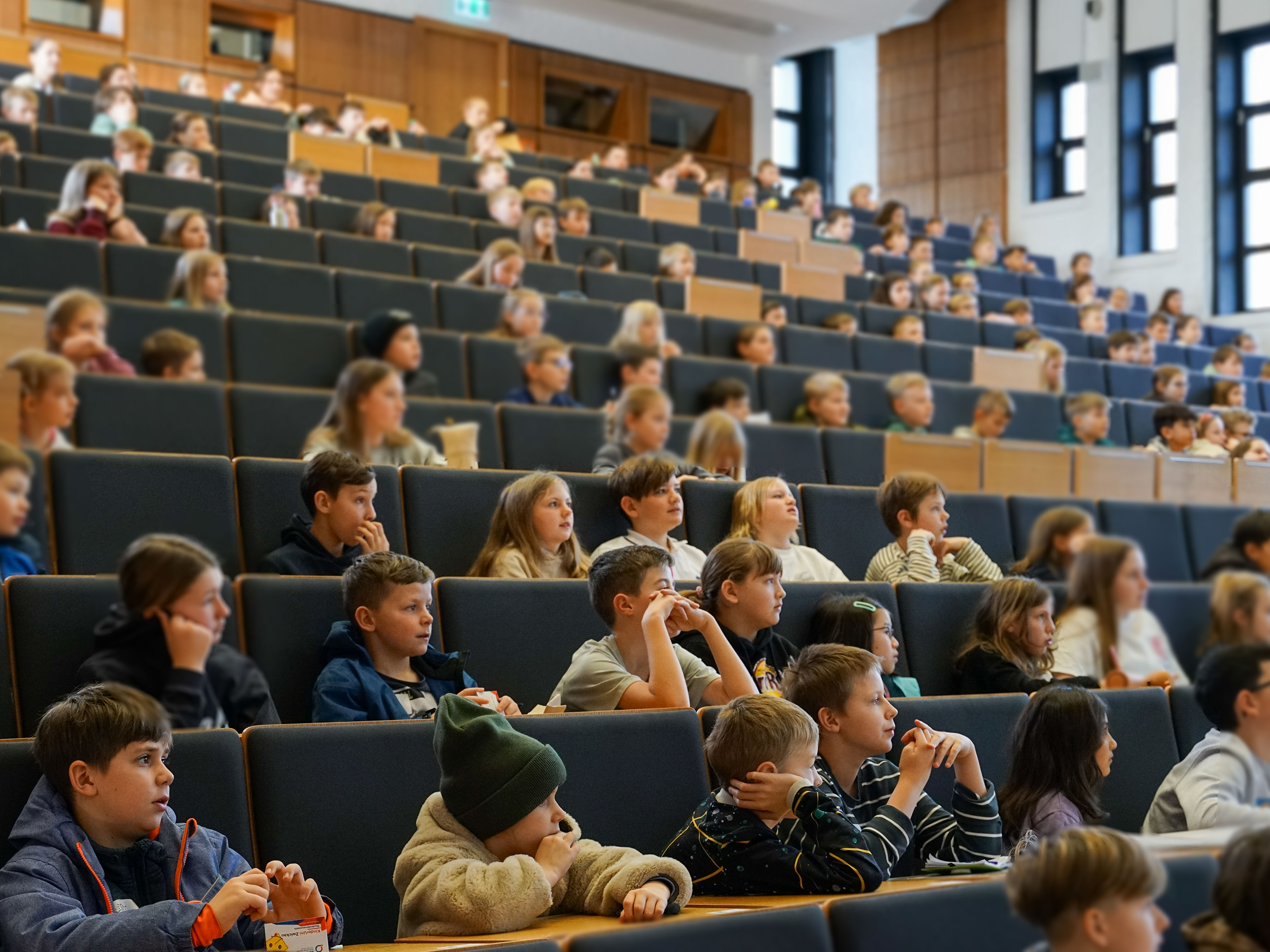 Kinder sitzen in einem Hörsaal. 