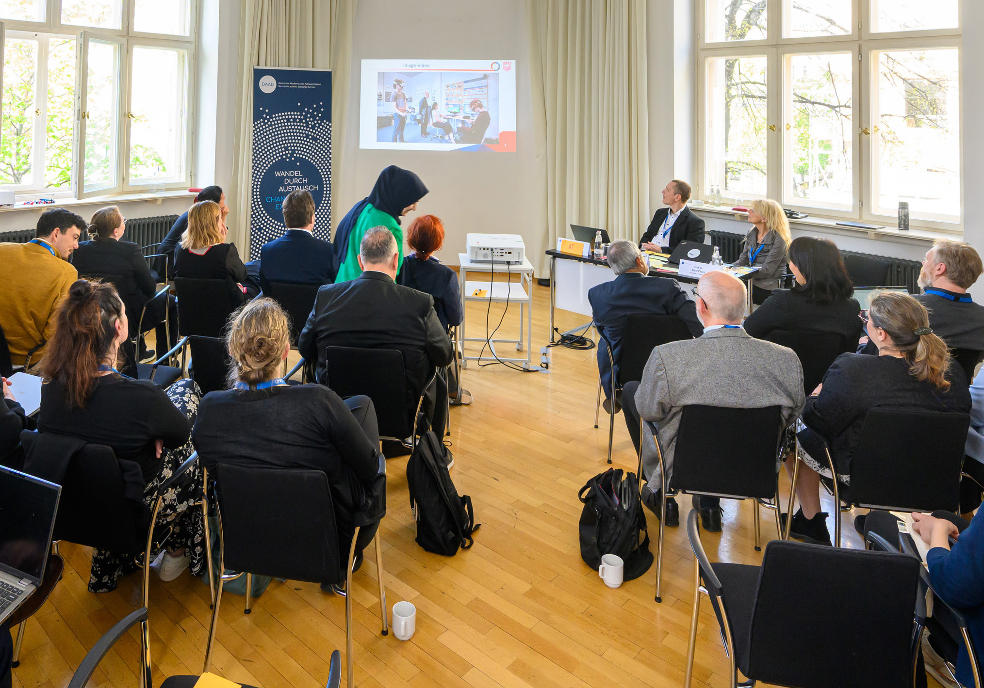 Personen präsentieren vor Zuhörern in einem Saal. 