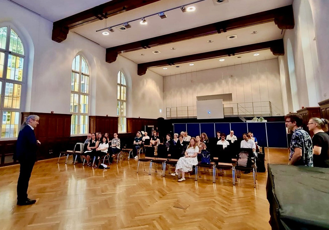 Rektor Prof. Kassel spricht in der Aula vor Publikum.