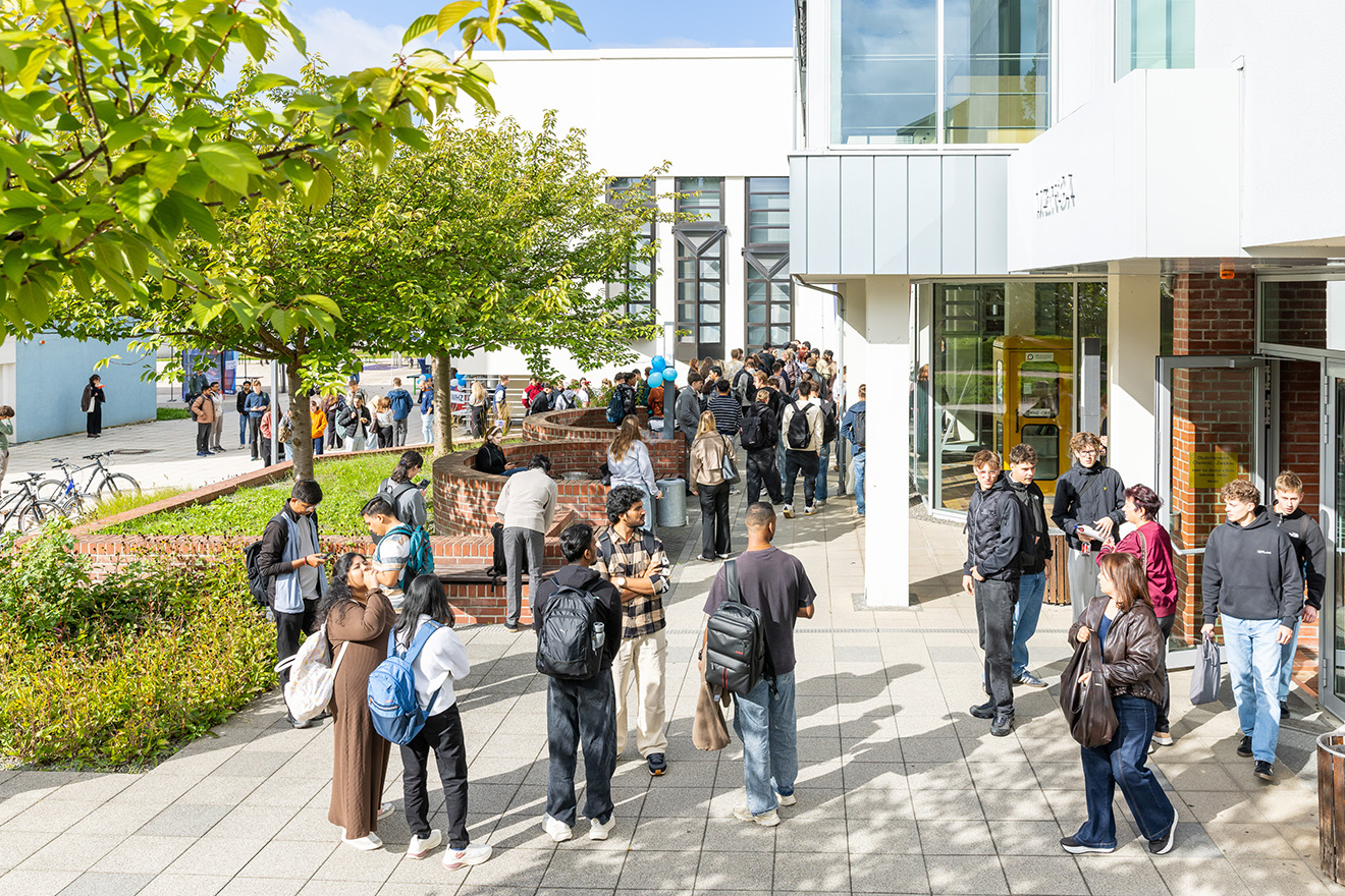 Studierende an einem sonnigen Tag vor dem Hörsaalzentrum der Westsächsischen Hochschule Zwickau. 