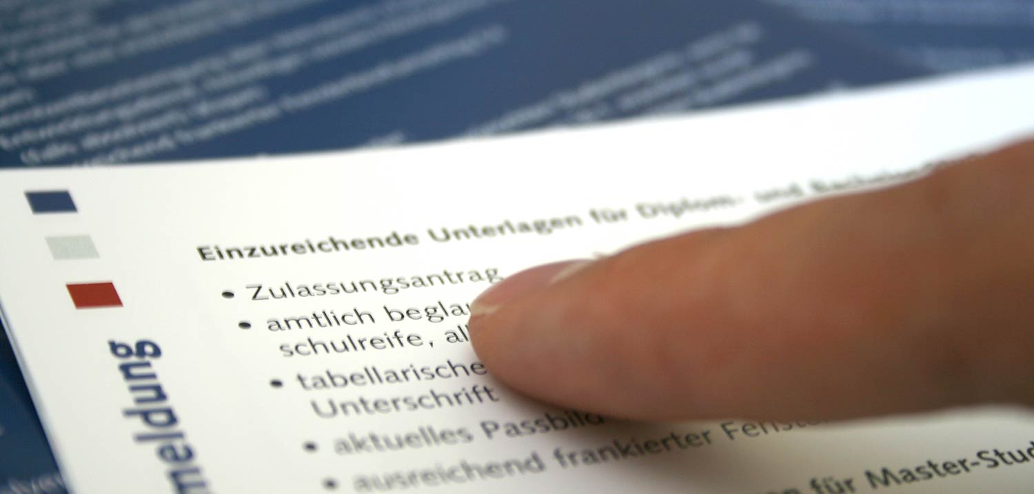 Ein Finger zeigt auf einem Informationsblatt auf das Wort "Zulassungsantrag".