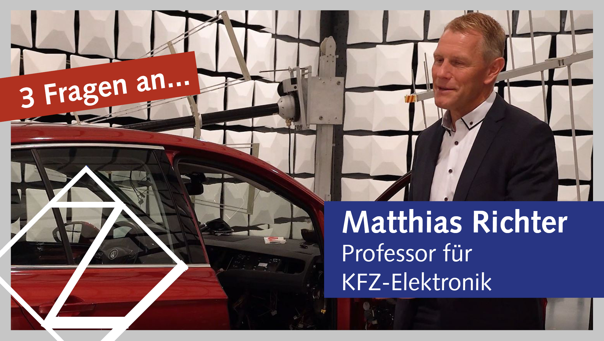 Professor Matthias Richter steht in einer futuristischen Laborhalle. Neben ihm ein rotes Fahrzeug, dessen Innenverkleidung teilweise abgebaut ist, sodass die sich dahinter befindliche Elektronik sichtbar wird. Auf das Fahrzeug sind mehrere Antennen gerichtet.