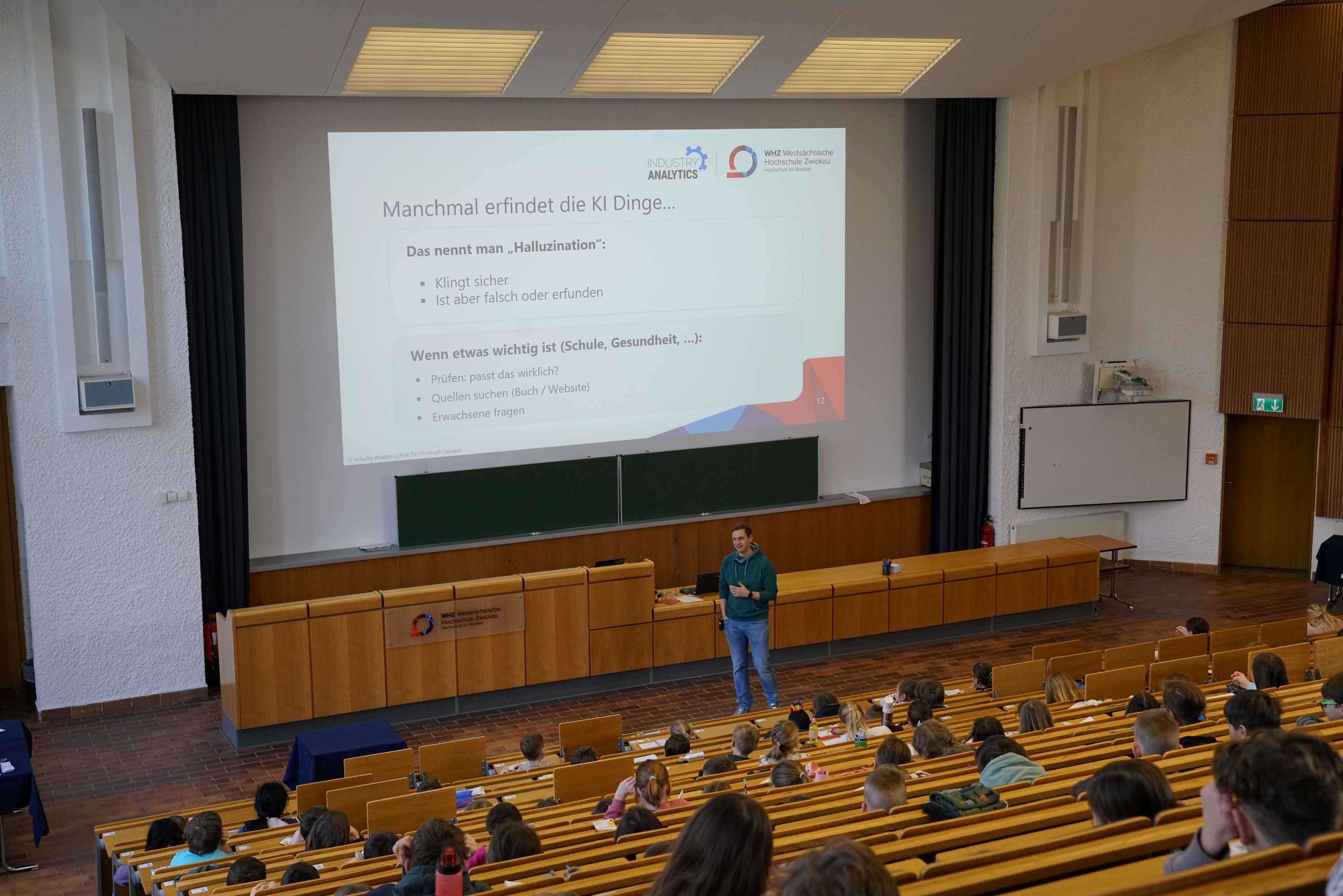 KinderUni 2026, Vorlesung zu KI, Blick in den vollen Hörsaal in Richtung des Professors