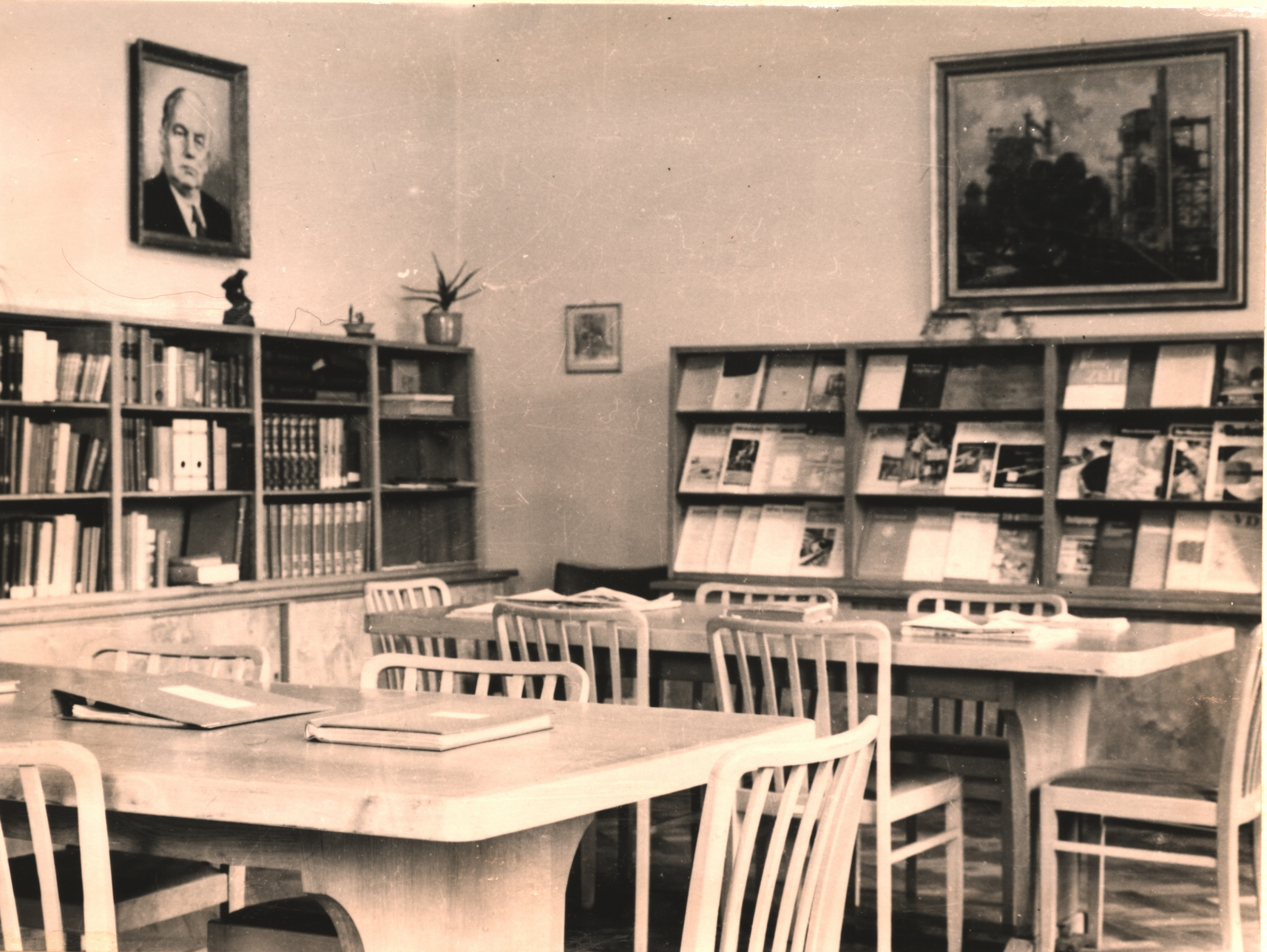 Blick in einen Lesesaal. Vor Tische im Hintergrund Bücherregale. 