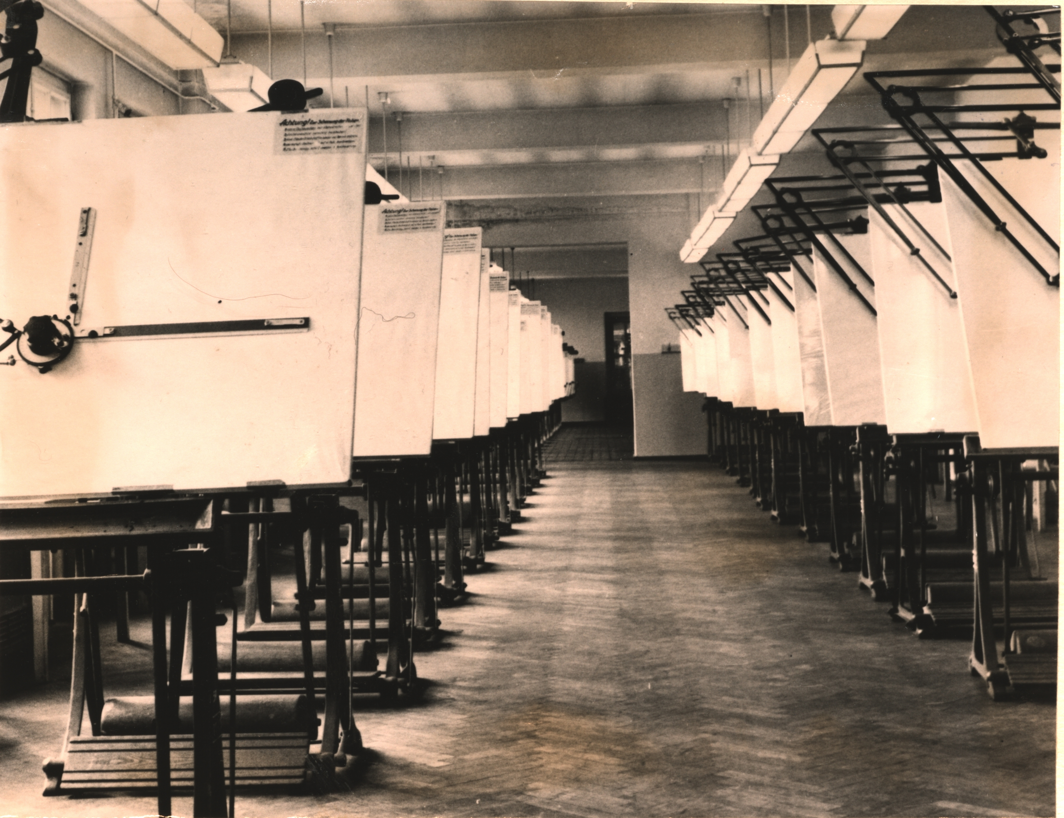Blick in einen langen Saal, links und rechts stehen Tafeln für das technische Zeichnen. 